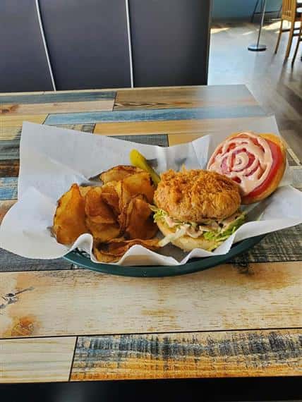 crispy fish sandwich on a bun with chipotle mayo, coleslaw, and tomato, side of fries