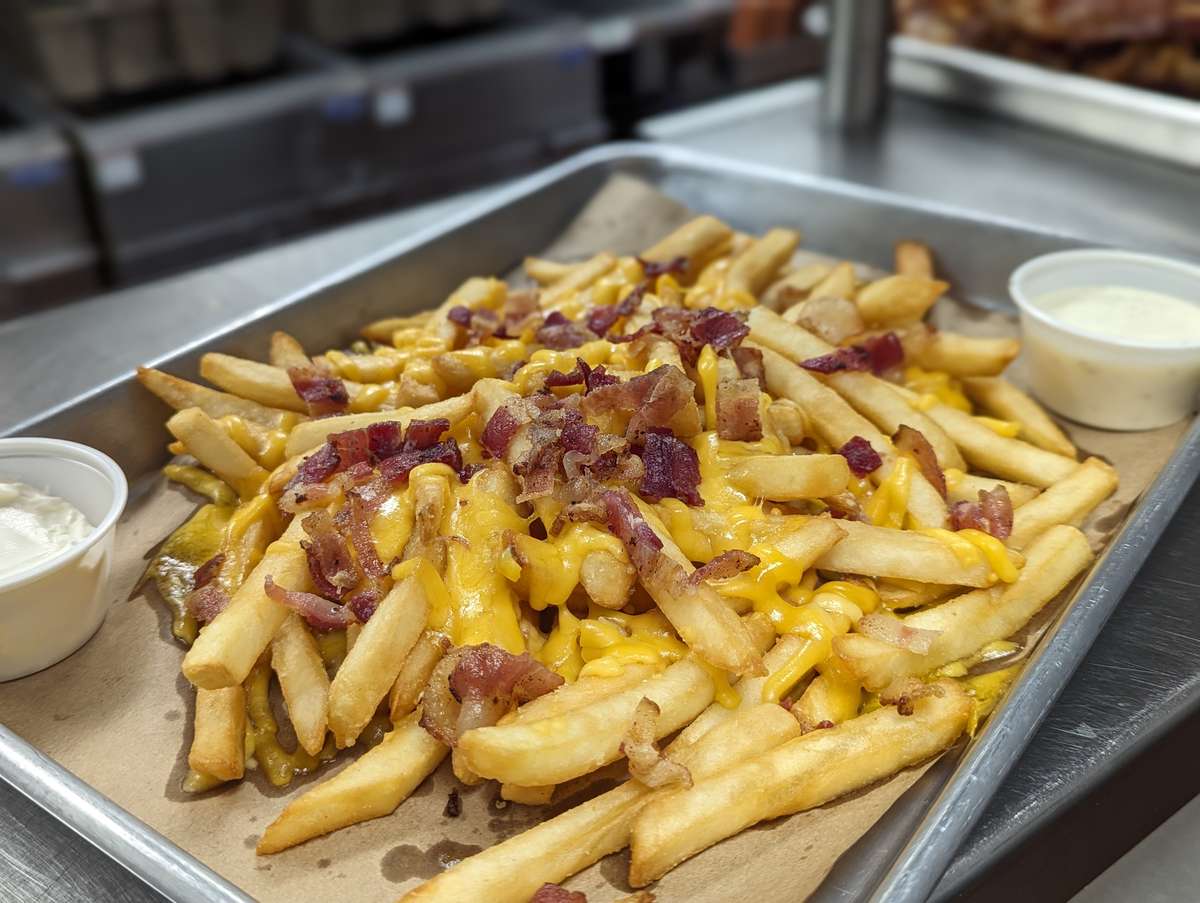 Basket of fries covered in melted cheddar cheese and hand chopped bacon bits.