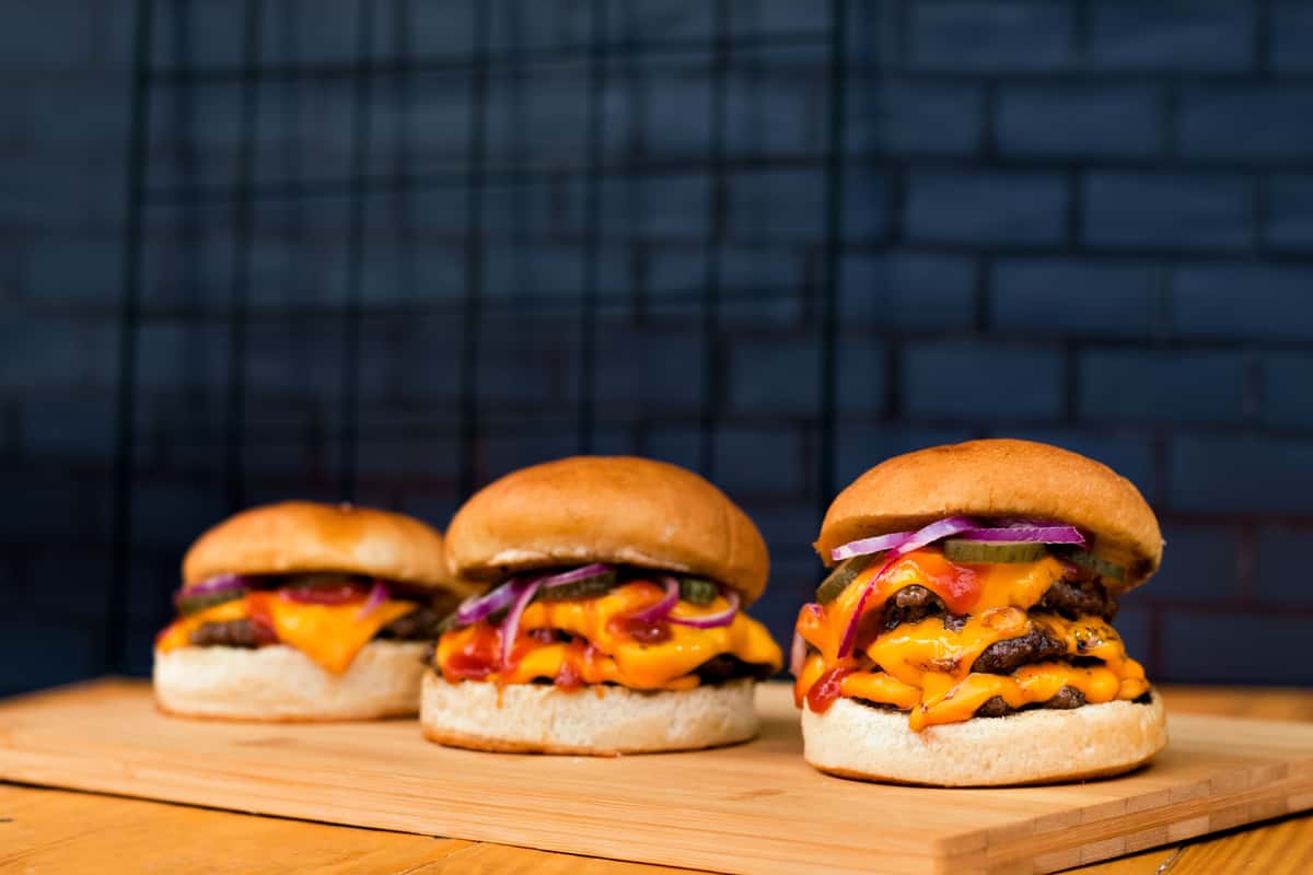 Indulge in three mouthwatering burgers loaded with cheese and toppings, perfect for food lovers.