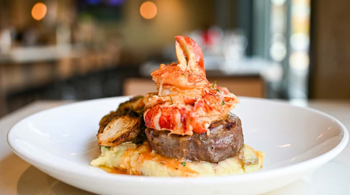 Surf and turf entrée with grilled filet steak, lobster tail, and creamy accompaniments at Novara in Milton