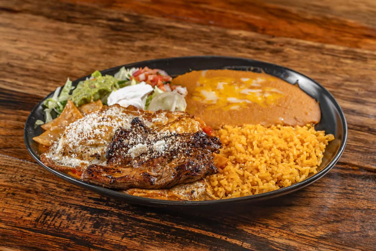 Fried tortilla chips are slowly simmered in green and red sauce, topped with two eggs and steak. Served with guacamole salad