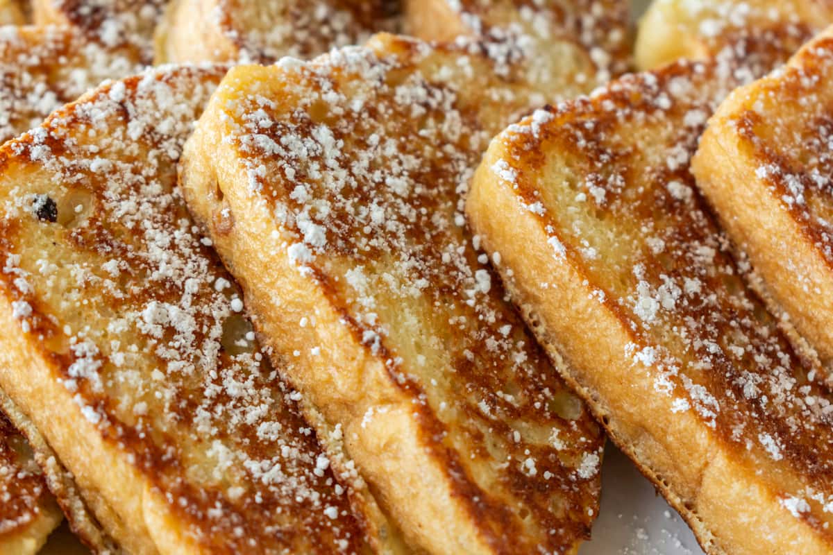 Close-up of thick-cut golden French toast slices dusted generously with powdered sugar — a classic breakfast favorite with a crispy exterior and soft, fluffy center.