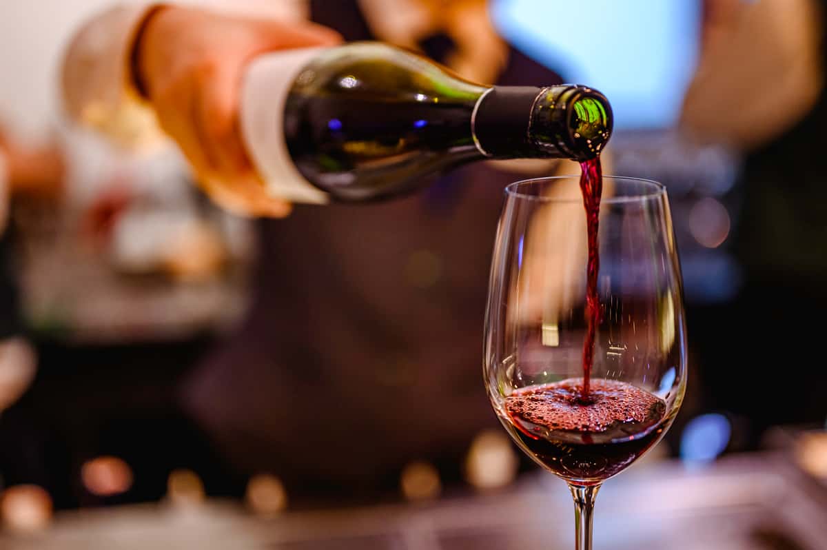 Close up of red wine being poured into a single wine glass