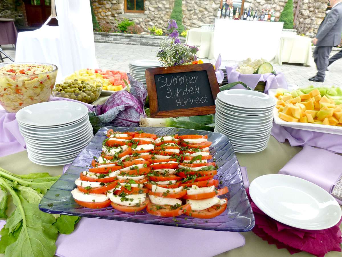 tomato and mozzarella on a platter with small plates and a sign that reads summer garden harvest