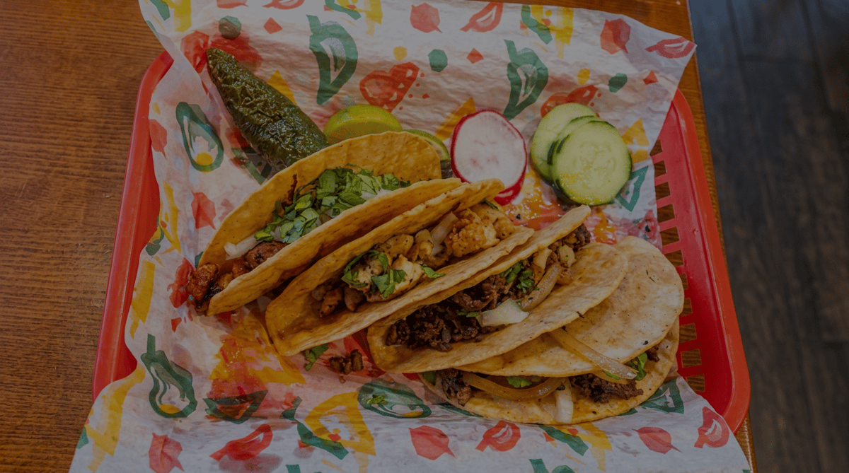 Authentic street tacos at El Cazo Mexican Restaurant filled with grilled chicken and seasoned steak, topped with fresh cilantro and onions, and served with a grilled jalapeño, lime, radishes, and cucumber.