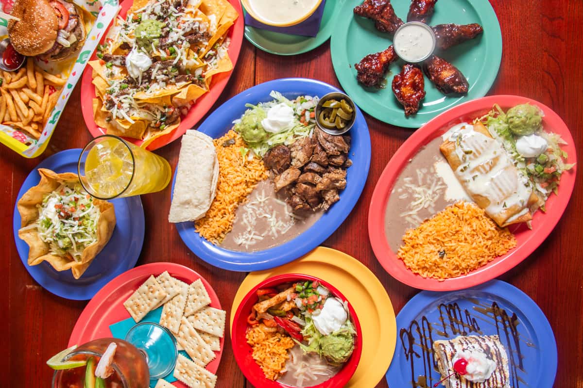 Overhead spread of El Cazo Mexican dishes on a wooden table