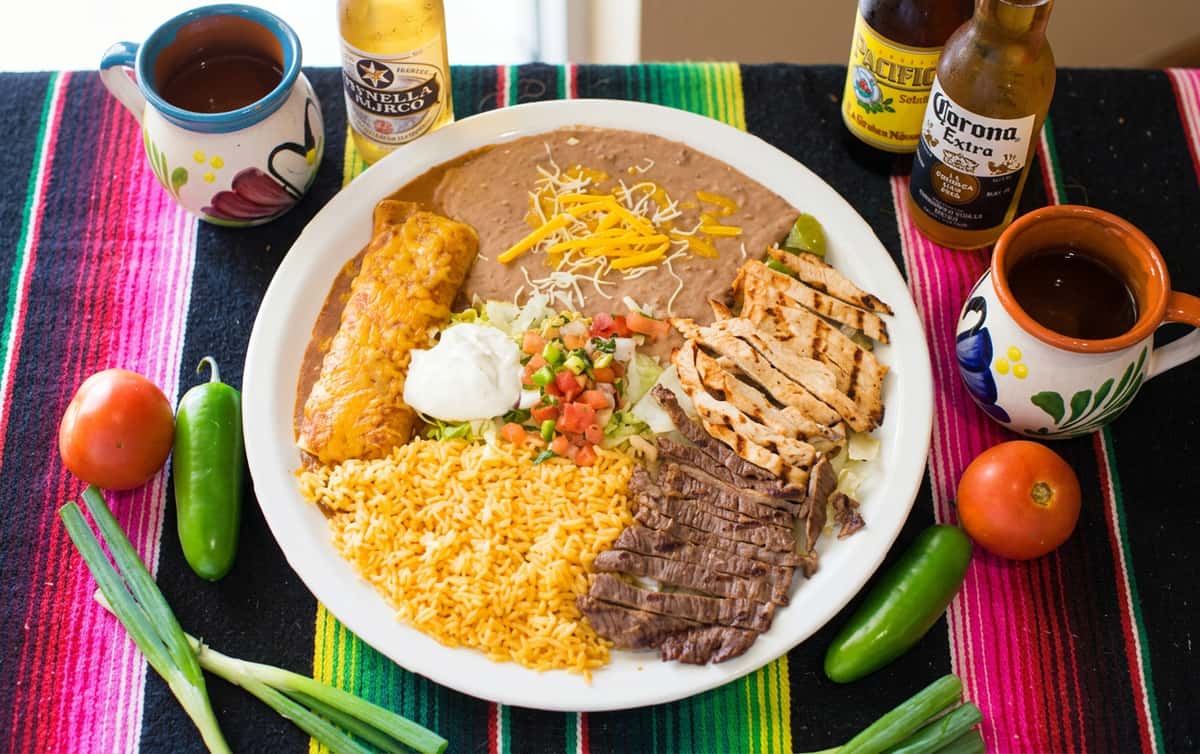 Mexican combo plate with beef, chicken, enchilada, rice, refried beans, pico de gallo, and sour cream.