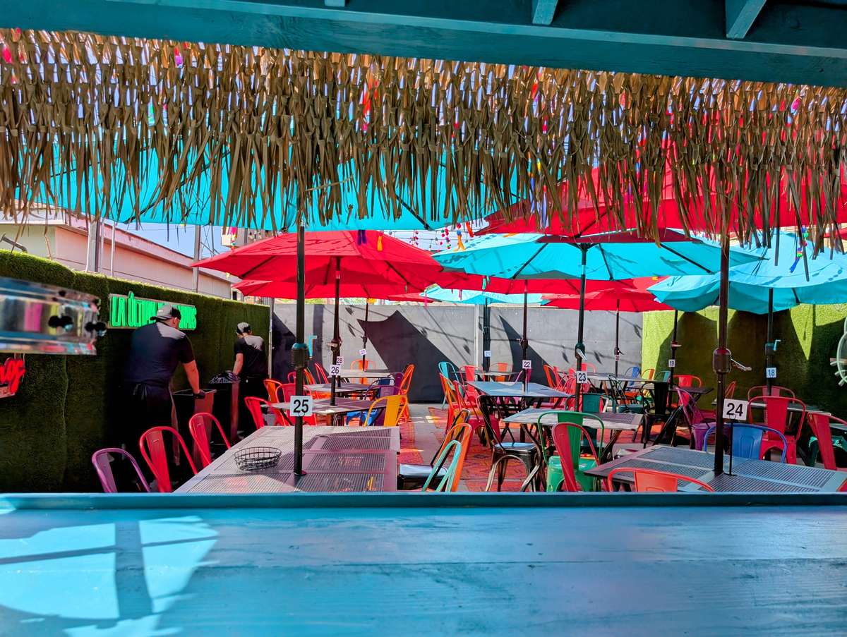 Vibrant outdoor patio dining showcases red and blue umbrellas shading tables