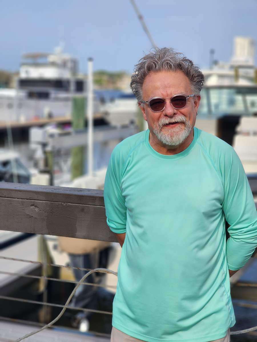 Cliff Doenges wearing a teal shirt in front of a boat dock