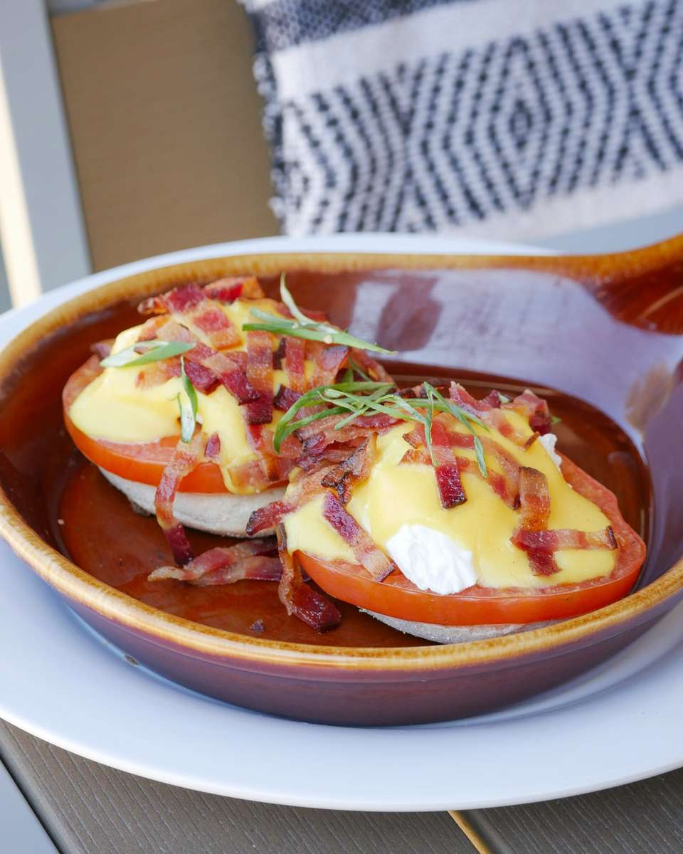 English muffin, grilled local tomato, topped with poached eggs, hollandaise, bacon, green onion, served with country potatoes