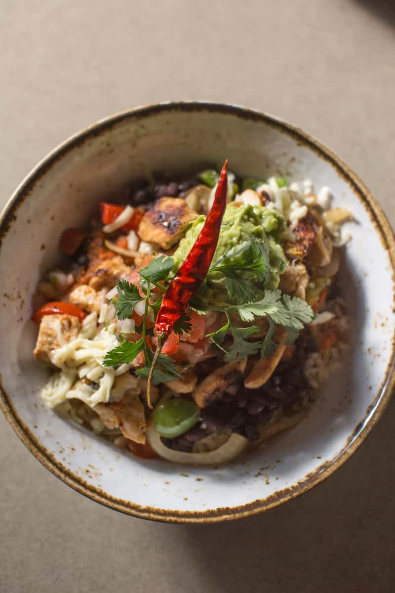 Grilled chicken bowl with white rice, black beans, grilled vegetables, Ranchera sauce, Pico de Gallo, guacamole and shredded cheese.