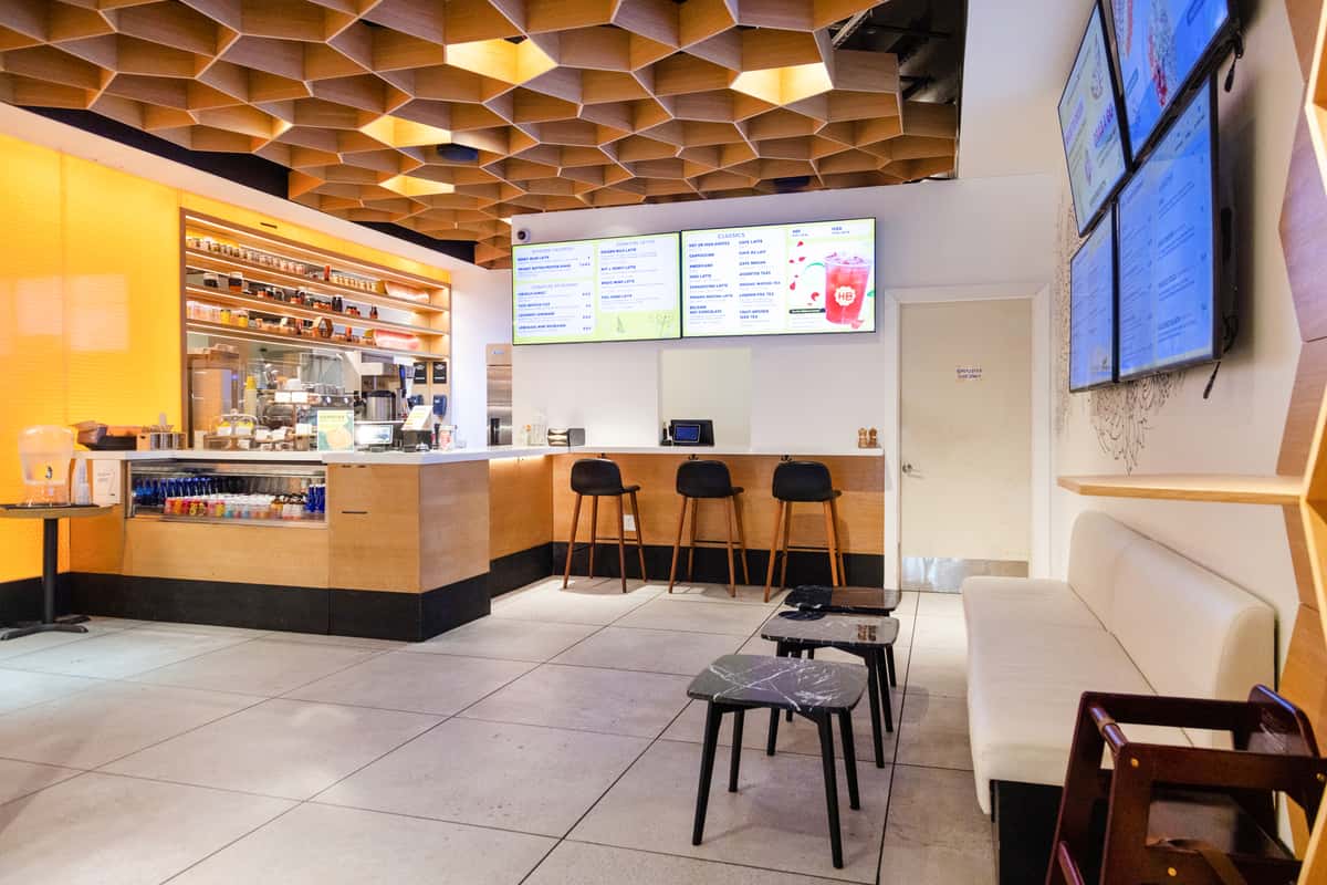 Bright contemporary café with digital menu boards, communal seating, and a welcoming fast-casual dining atmosphere.