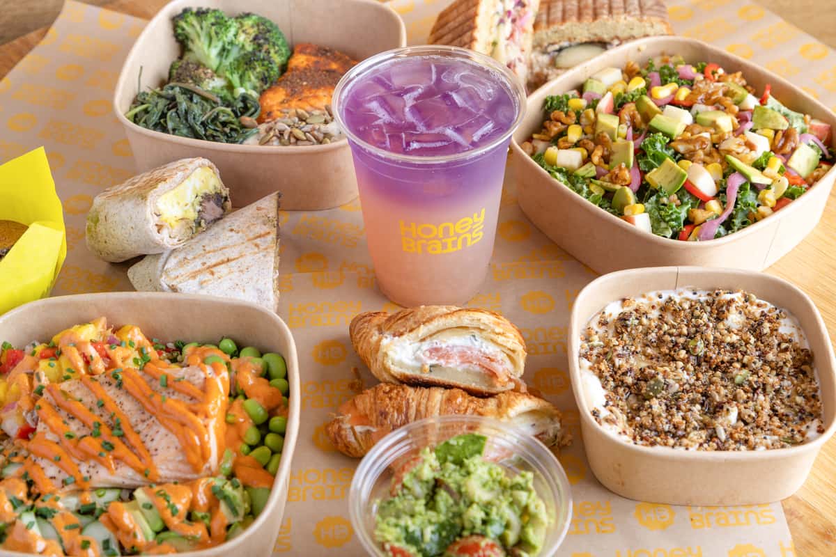 Signature café spread featuring fresh salads, grain bowls, wraps, pastries, and handcrafted beverages for healthy dining and catering.