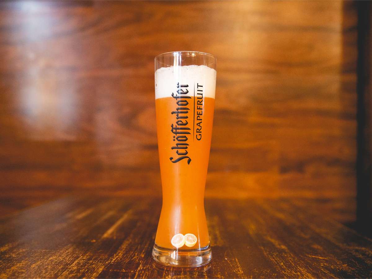 Schöfferhofer Grapefruit Hefeweizen served in a tall branded glass with a foamy head, offering a refreshing blend of German wheat beer and grapefruit flavor at Berliner Pub.