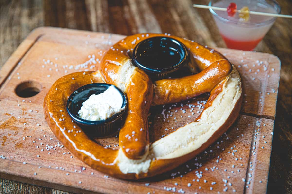 Warm Bavarian dessert pretzel dusted with powdered sugar and served with chocolate and cream dipping sauces at Berliner Pub.
