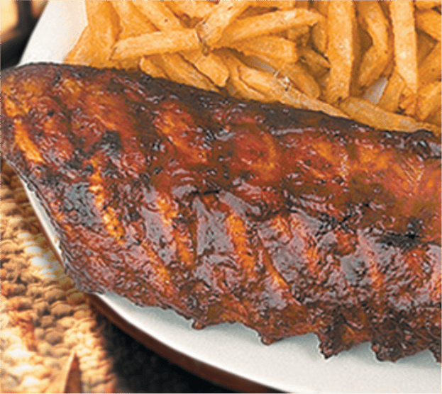 full rack of ribs covered in barbecue sauce. french fries on the side.