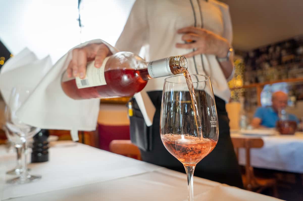 server pouring a glass of wine'