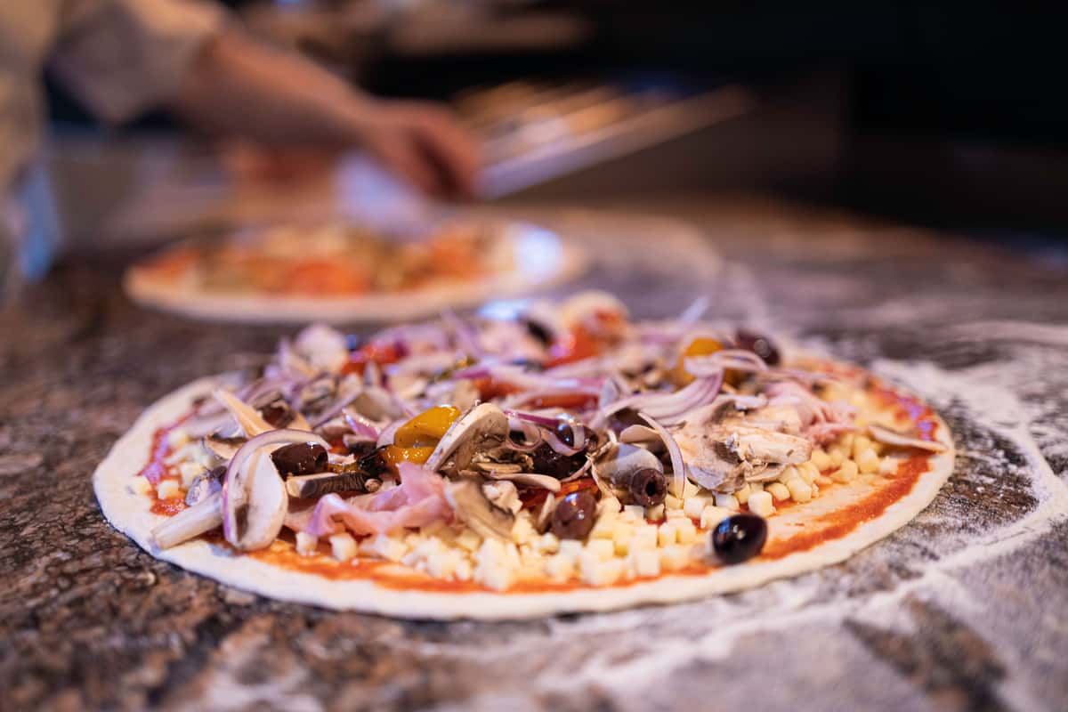 Stone-baked pizza topped with fresh vegetables and olives