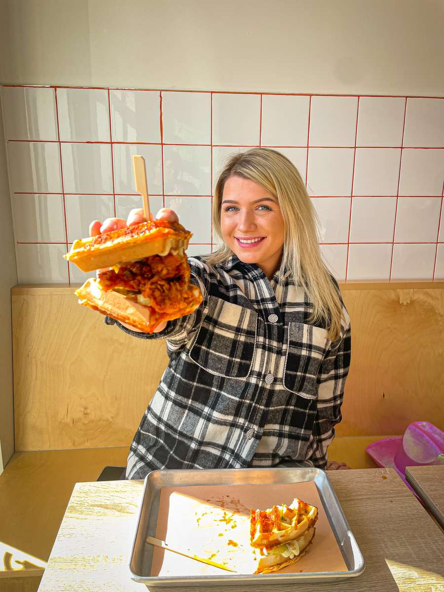 Person holding chicken and waffles sandwich
