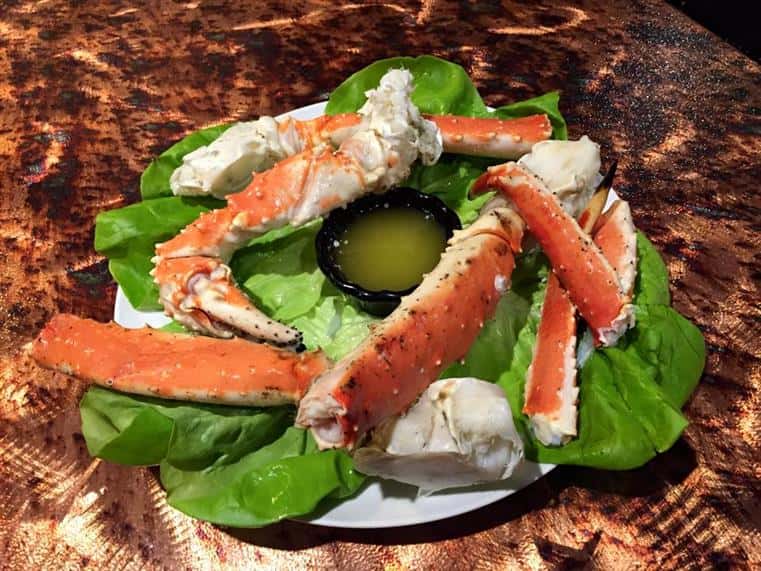 Giant king crab legs with butter sauce over lettuce.