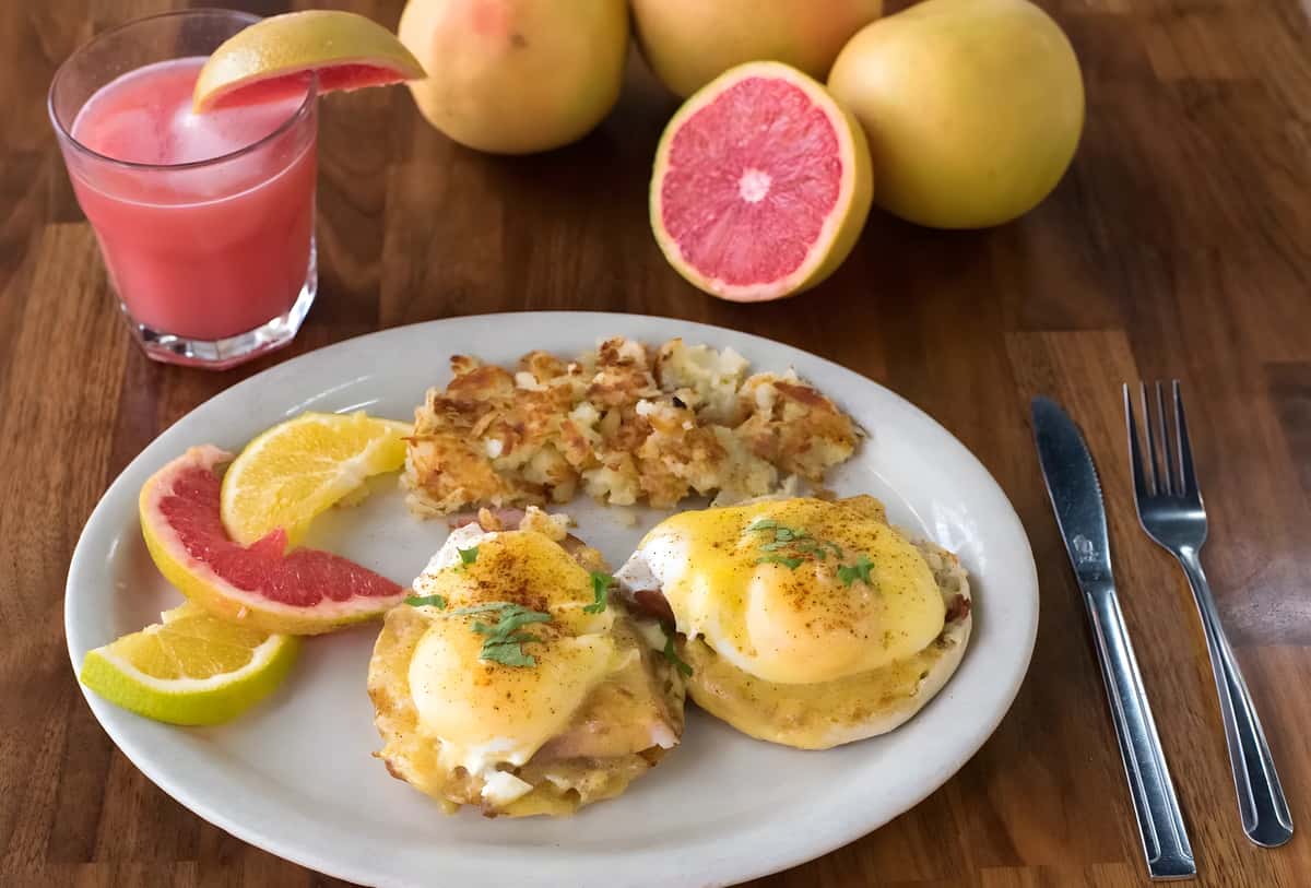 Eggs Benedict served with breakfast potatoes and fresh fruit.