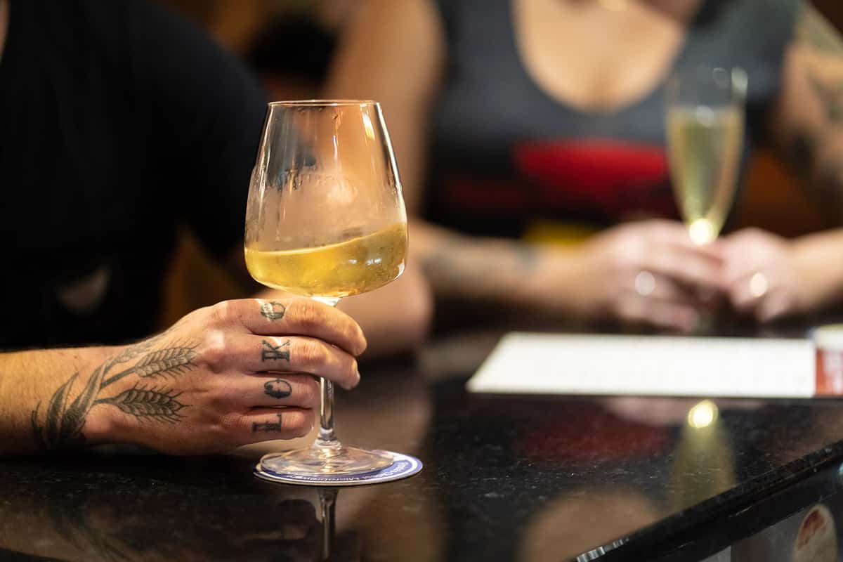 tattoed hand with wine glass