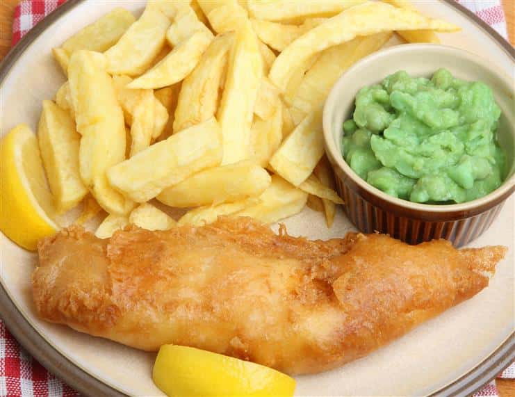 fried fish with a lemon wedge, a side of french fries and another side item