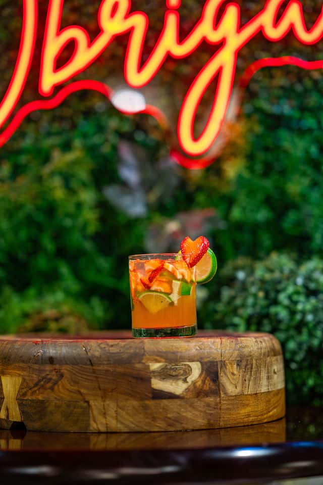 Strawberry Lime Caipirinha sitting on a wooden pedestal.