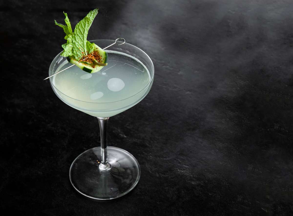 Pale green craft cocktail garnished with fresh mint and spiced cucumber slice in a coupe glass, served at Jonathan the rub.