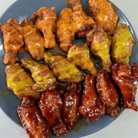 plate of wings with three different types of sauces