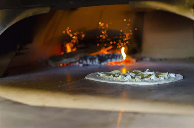 Pizza cooking in wood fired pizza oven