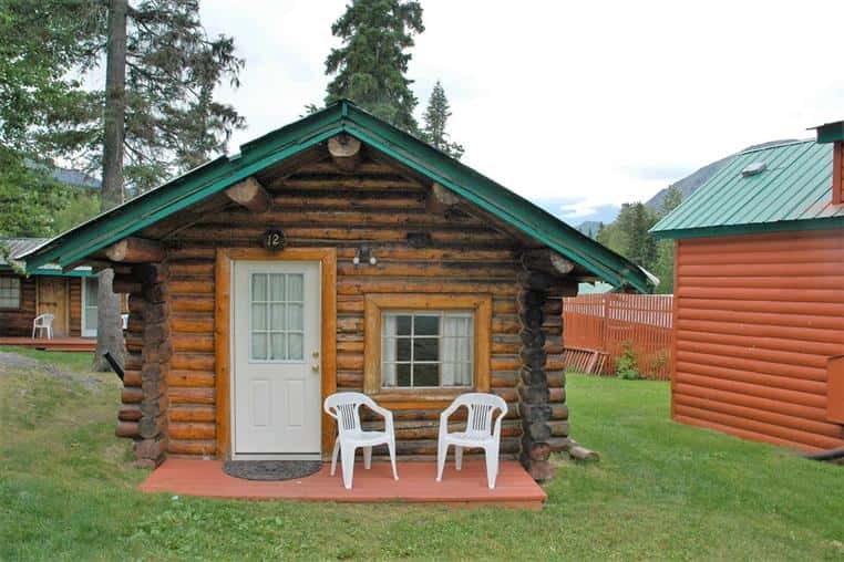 fir log cabin front entrance with two white chairs