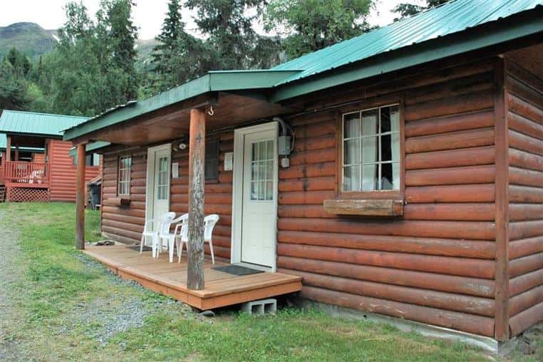 willow log cabin front entrance with three white chairs