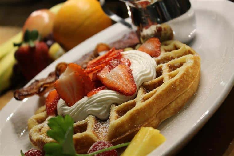 Belgian waffle topped with cream and strawberries