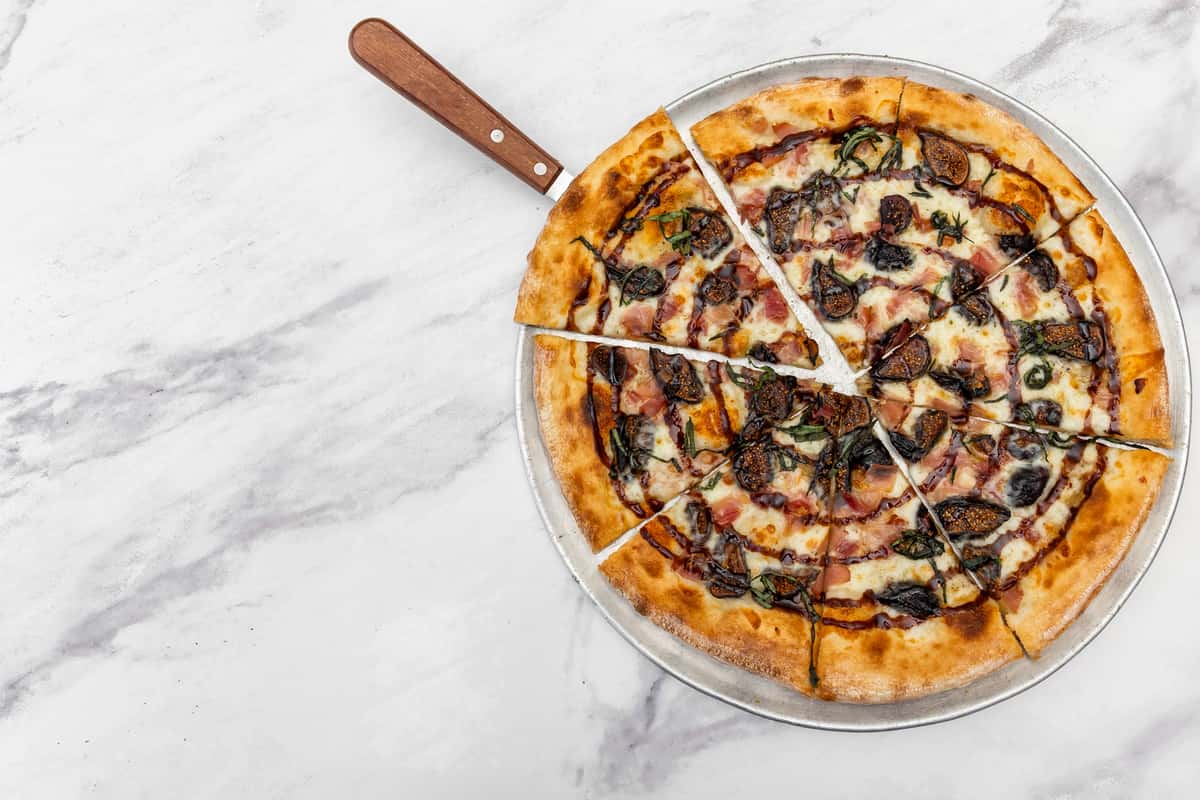 gourmet specialty pizza with mixed toppings, olives, and melted cheese on a crispy crust