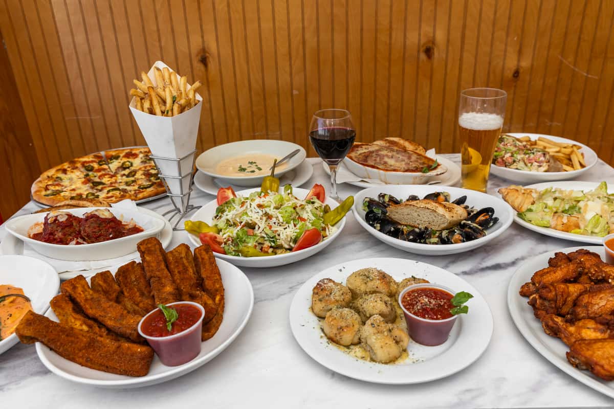 top-down spread of assorted italian dishes including pasta, pizza, salads, and appetizers on a table