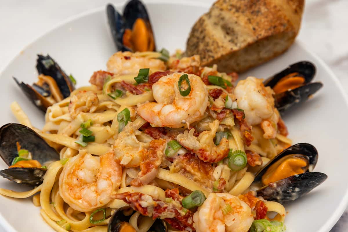 seafood pasta with shrimp and mussels tossed in a savory sauce with herbs and vegetables
