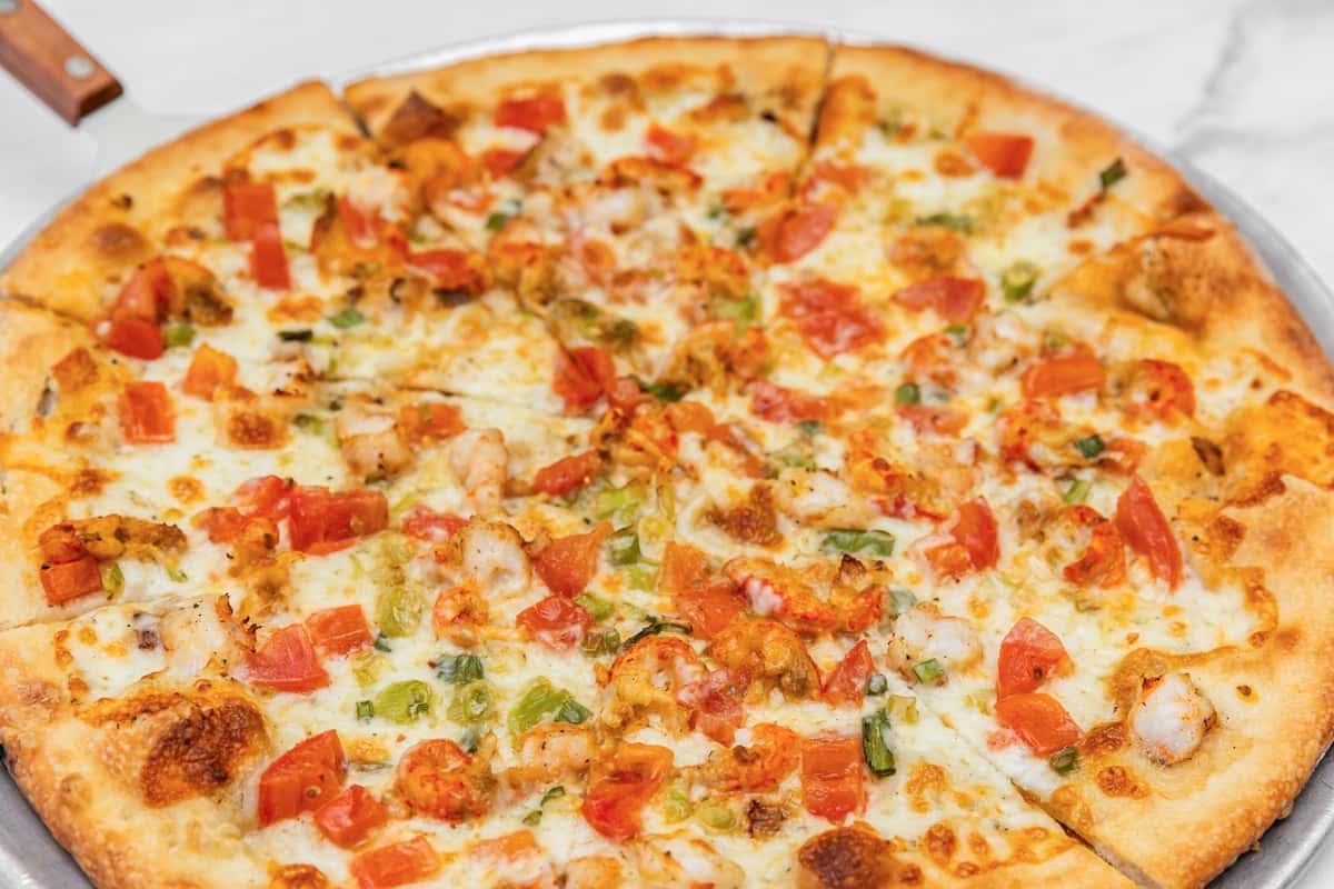 seafood pizza topped with shrimp, calamari, and herbs over melted cheese on thin crust