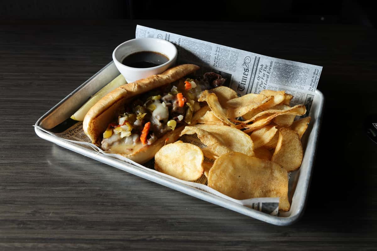 Philly cheesesteak sandwich with potato chips and au jus sauce