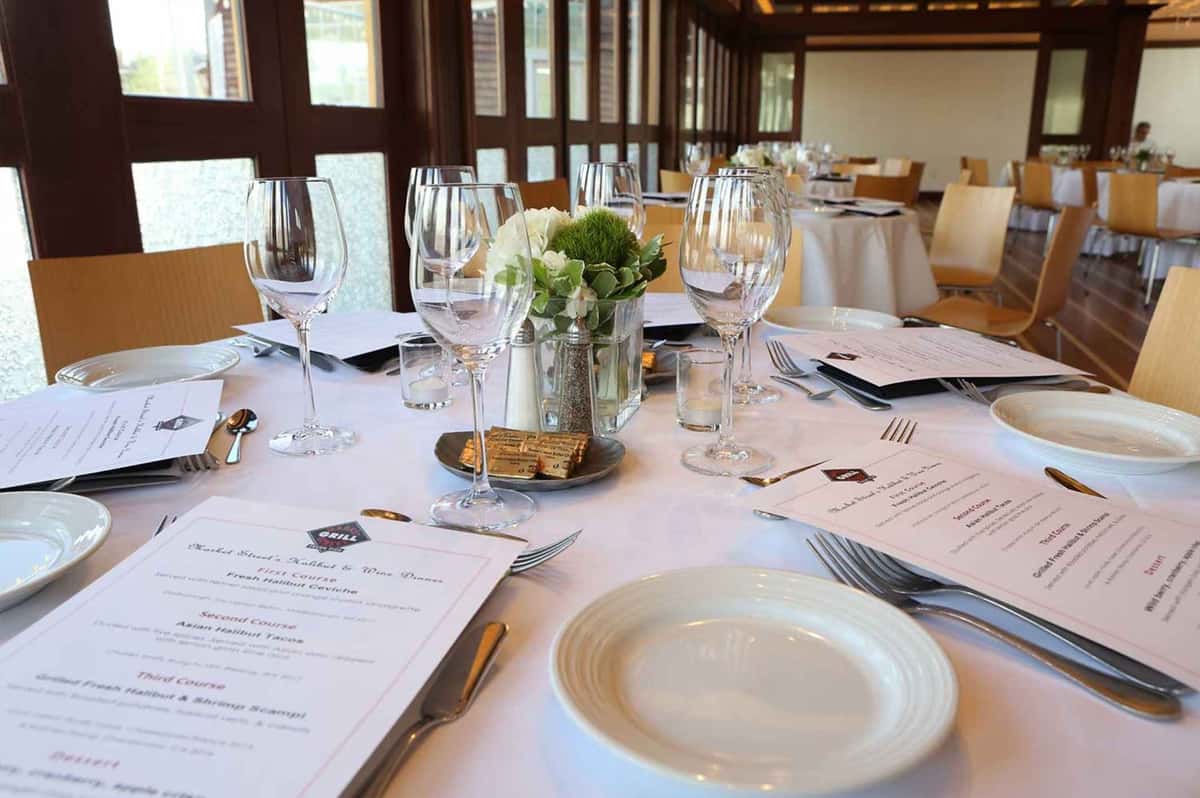 A private dining event table setting with personalized menus, fine dining wear and flowers.