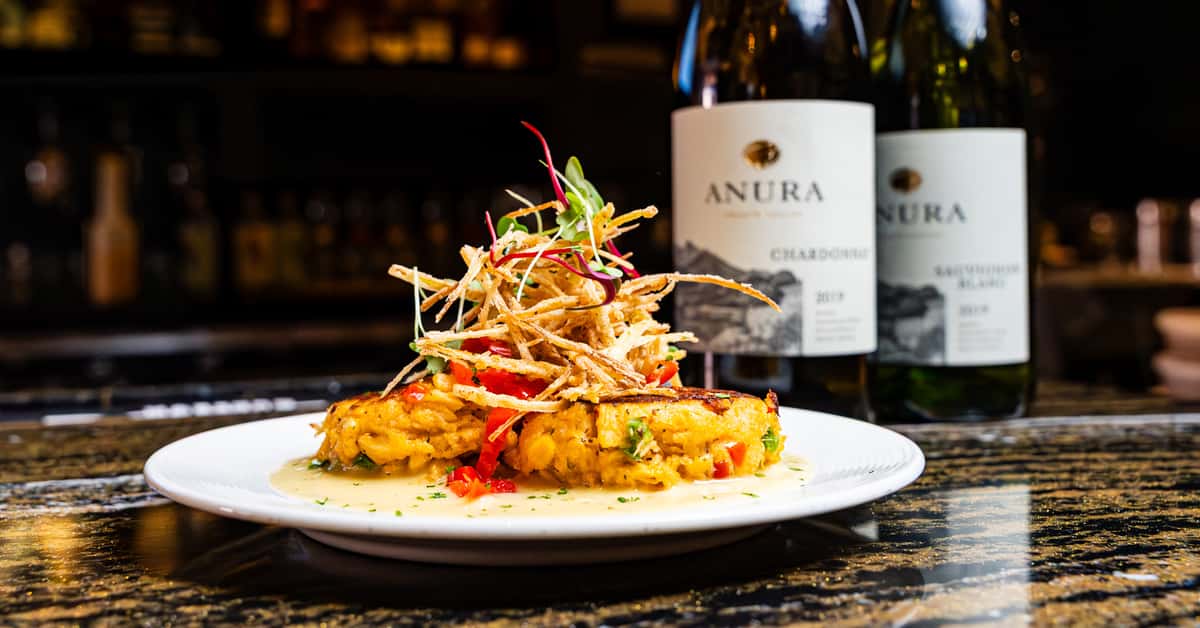 Artfully plated food with bottles of wine