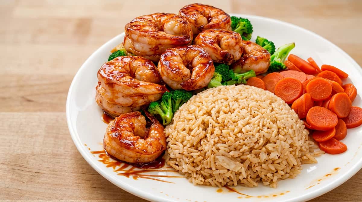 Glazed shrimp with seasoned rice and vegetables served on a hearty dinner plate