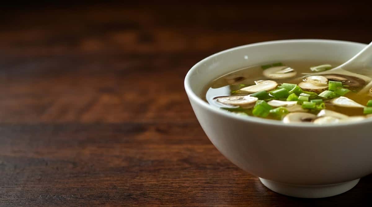 Warm mushroom soup garnished with sliced green onions and served in a white bowl