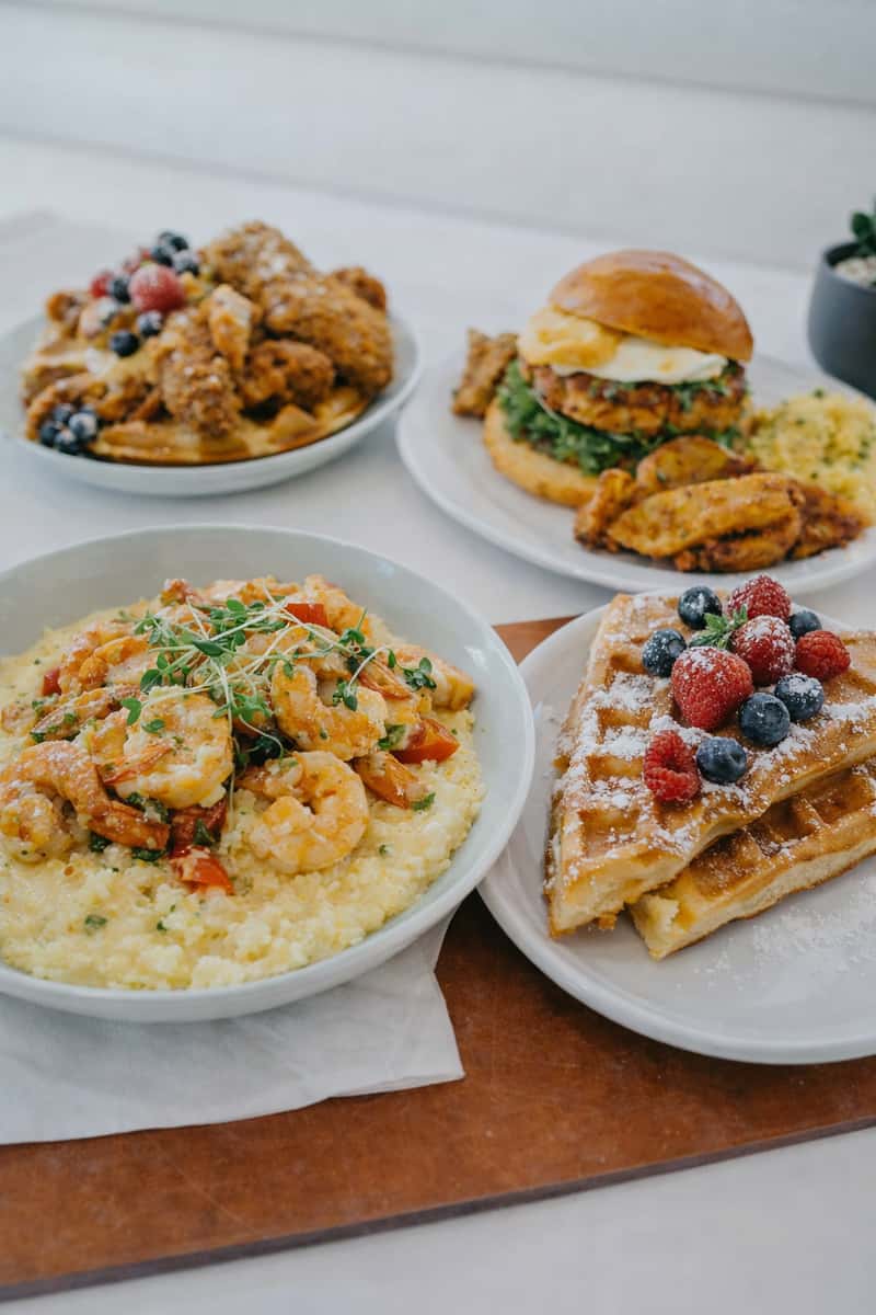 Breakfast spread with rice dish, waffles, burger, fried chicken, and pancakes with berries.