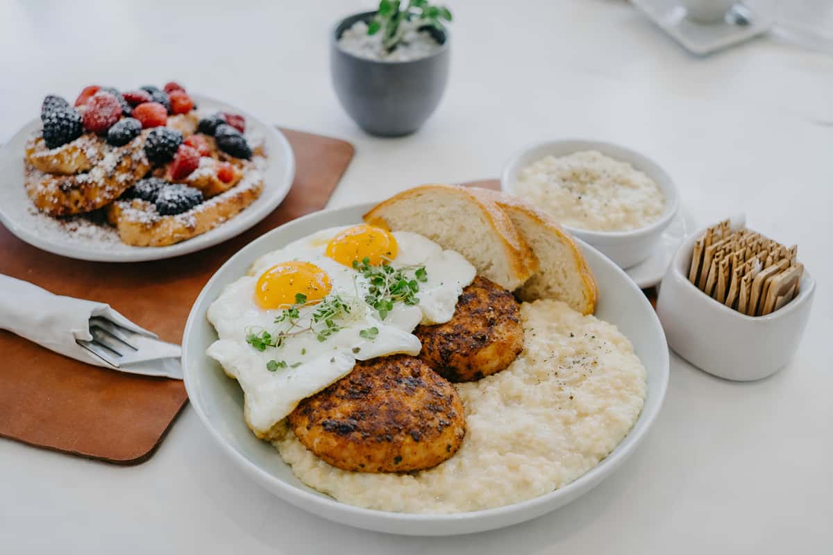 Breakfast plate with two sausage patties, white gravy, rice, and two fried eggs.
