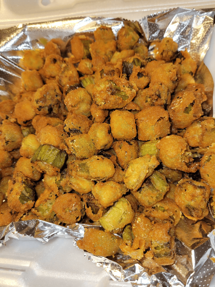 Golden-fried okra bites served over foil in a takeout tray — a crunchy and seasoned Southern comfort food side dish.