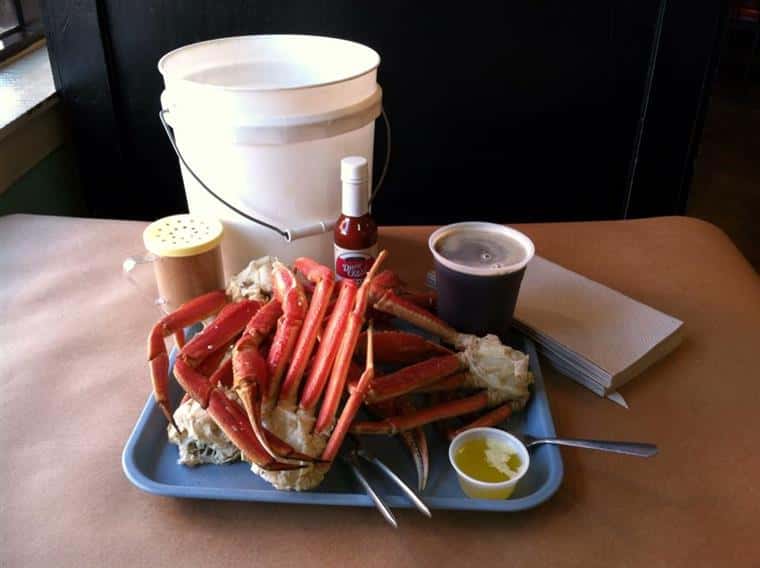 Crab legs with claw crackers and butter on a tray. Hot sauce, drink, napkins.