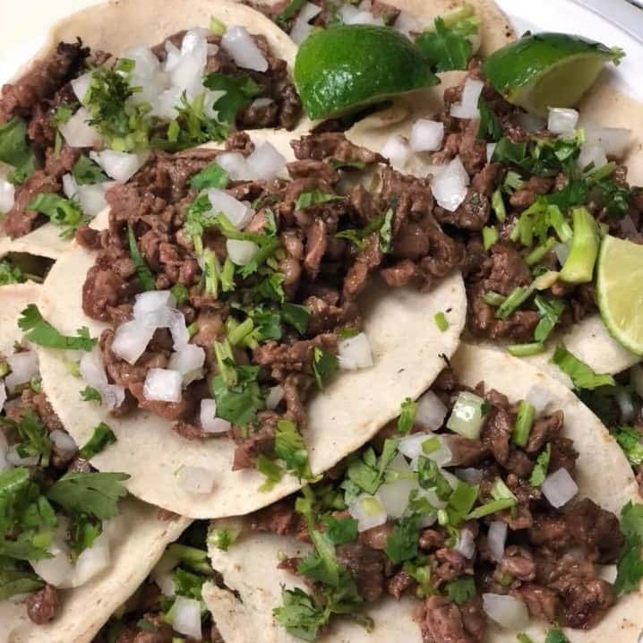 Steak street tacos stack on each other with cilantro, onion and lime