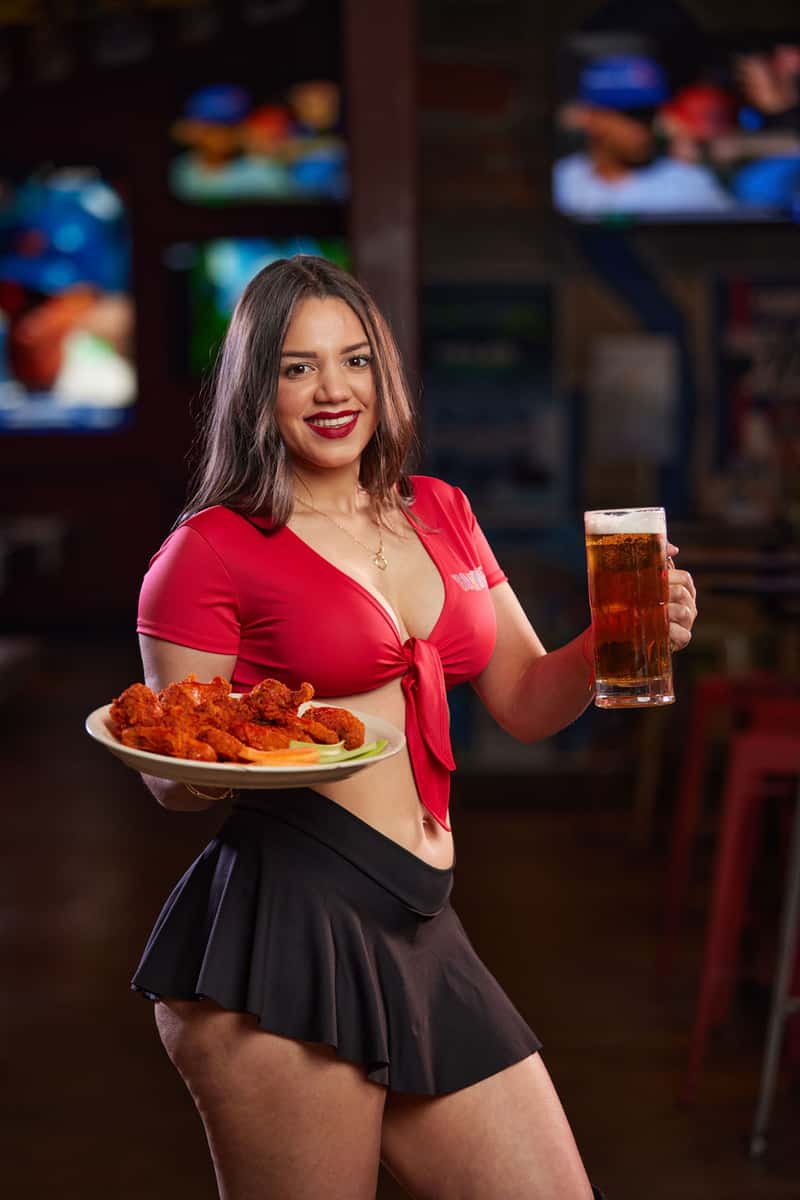 Waitress holding a plate of wings and beer