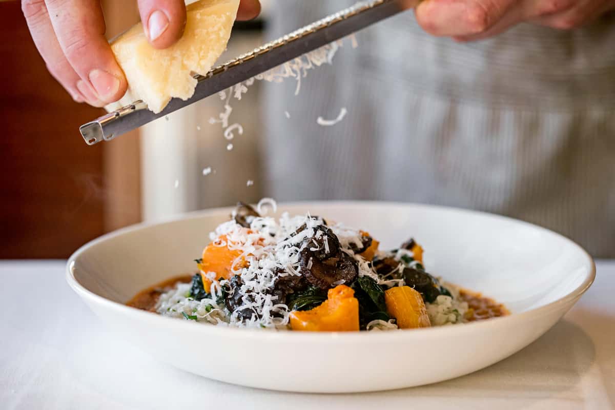 Chef grating cheese over a plate of food